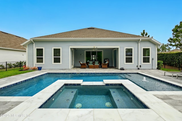 rear view of house featuring a pool with connected hot tub, fence, outdoor lounge area, and a patio area