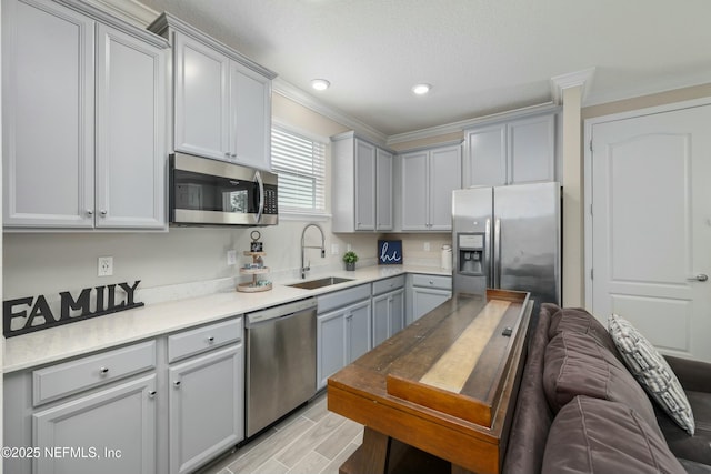 kitchen featuring gray cabinets, a sink, stainless steel appliances, and crown molding