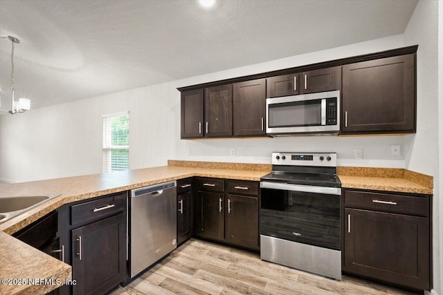 7271 Gateway Ct, Jacksonville, FL 32219 - kitchen with stainless steel appliances, light wood-style floors, dark brown cabinetry, pendant lighting, and light countertops
