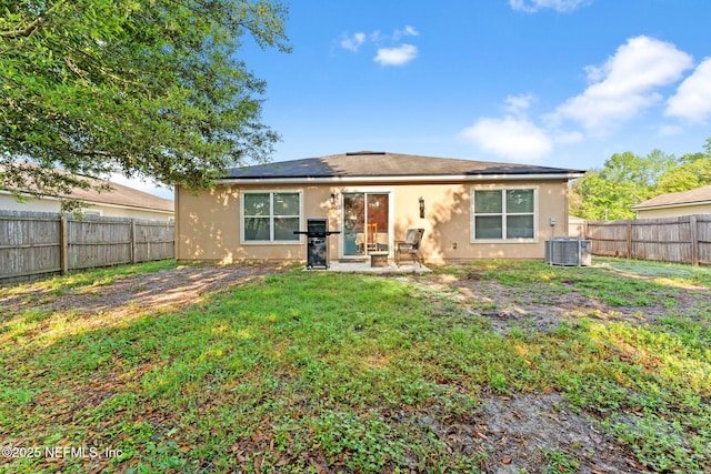 9087 Leicestershire Ct, Jacksonville, FL 32219 - back of house with central air condition unit, stucco siding, a lawn, a fenced backyard, and roof mounted solar panels