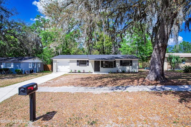 single story home with driveway, a garage, and brick siding