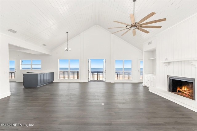 unfurnished living room featuring dark wood finished floors, high vaulted ceiling, a lit fireplace, and ceiling fan with notable chandelier