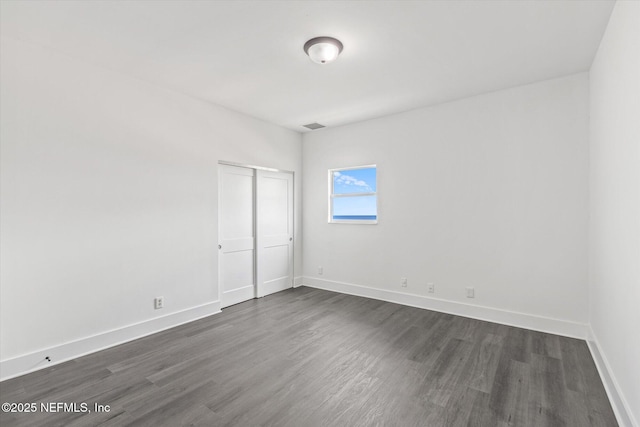 interior space featuring a closet, baseboards, visible vents, and dark wood-style floors