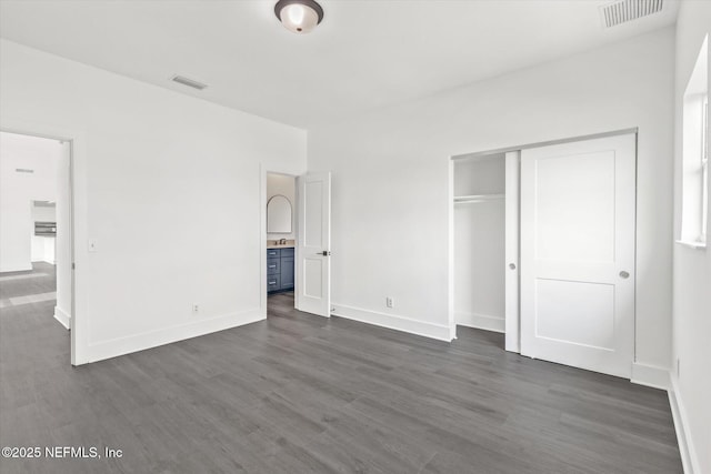 unfurnished bedroom with dark wood-type flooring, visible vents, and a closet