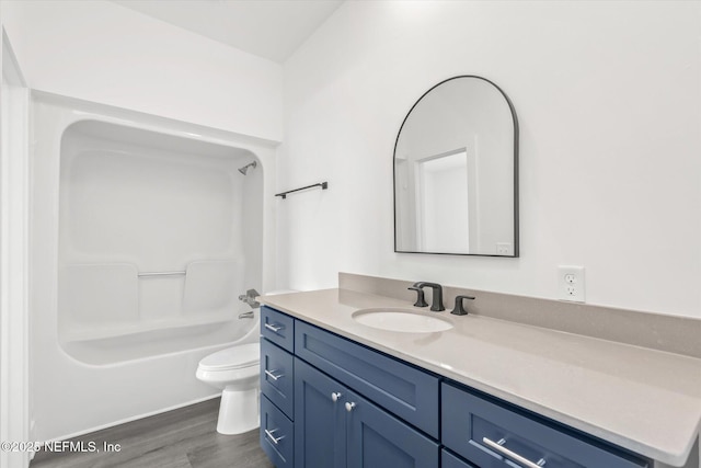 full bathroom featuring toilet, wood finished floors, vanity, and shower / washtub combination
