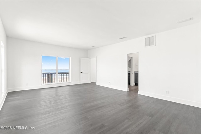 empty room featuring visible vents, baseboards, and dark wood finished floors