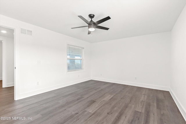 empty room featuring ceiling fan, baseboards, dark wood finished floors, and visible vents