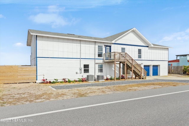 view of front of home featuring concrete driveway, stairs, central AC, and fence