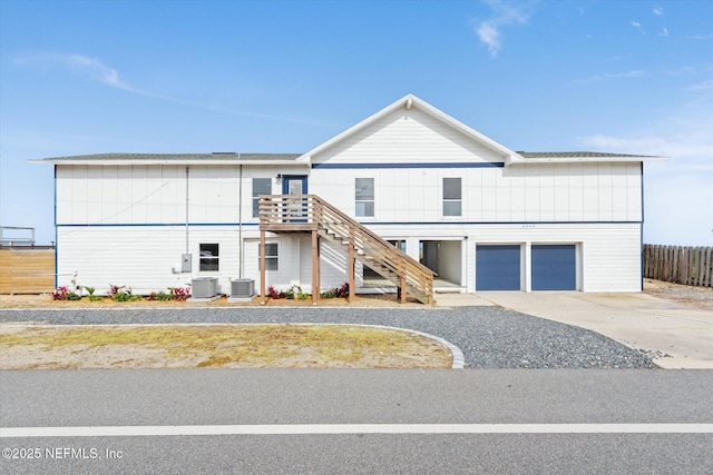 view of front of home with a garage, cooling unit, stairway, fence, and driveway