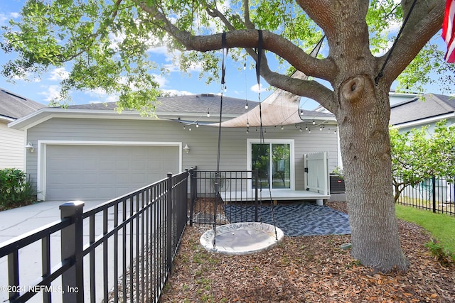 rear view of property featuring a shingled roof, an attached garage, fence, and concrete driveway