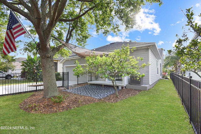 rear view of house featuring fence, an attached garage, and a lawn