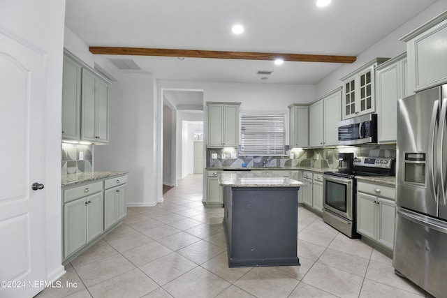 kitchen with decorative backsplash, beam ceiling, appliances with stainless steel finishes, light stone counters, and a center island