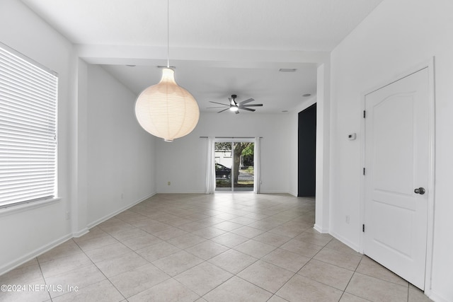 empty room featuring baseboards, ceiling fan, and light tile patterned floors