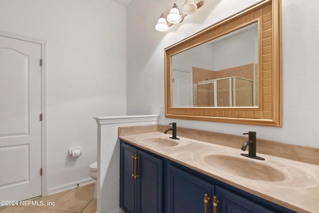 full bath featuring a shower stall, double vanity, toilet, a sink, and tile patterned flooring