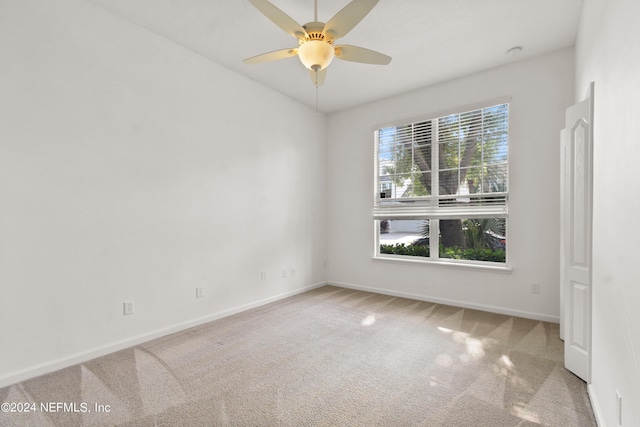 spare room with baseboards, ceiling fan, and carpet