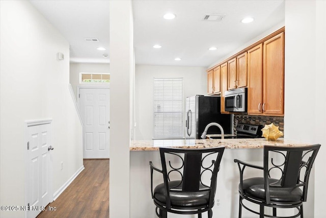 1492 Fieldview Dr, Jacksonville, FL 32225 - kitchen featuring a kitchen breakfast bar, dark wood-style floors, tasteful backsplash, and appliances with stainless steel finishes