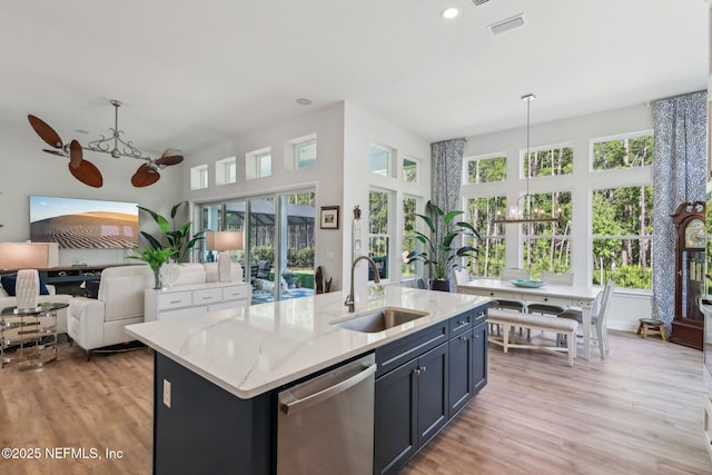 kitchen with a sink, open floor plan, stainless steel dishwasher, and light wood-style flooring