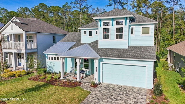 view of front of home with an attached garage, a shingled roof, a front lawn, and decorative driveway