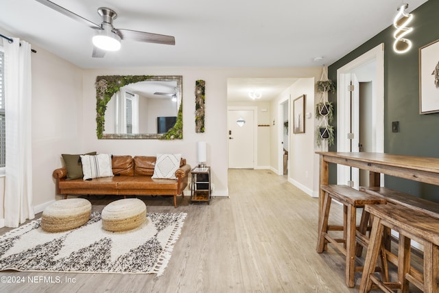 living room with baseboards, wood finished floors, and a ceiling fan