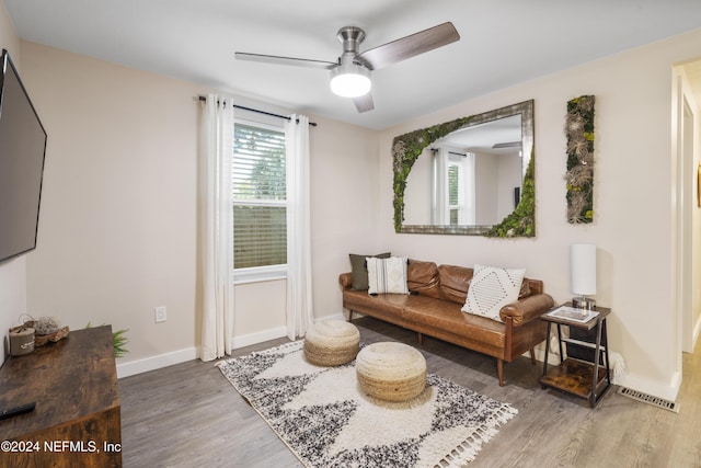 living area featuring baseboards, visible vents, wood finished floors, and ceiling fan