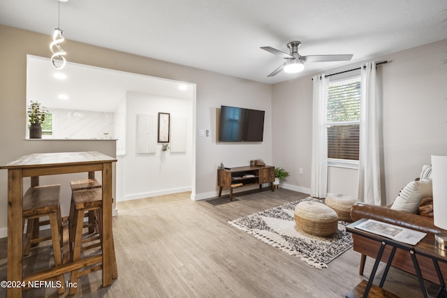 living room with baseboards, wood finished floors, and a ceiling fan