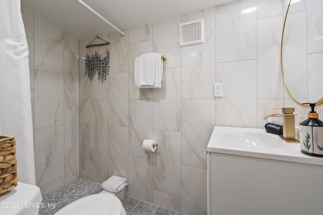 bathroom featuring tile walls, visible vents, toilet, a tile shower, and vanity