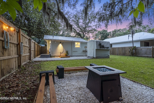 view of yard with an outdoor fire pit, a fenced backyard, an outbuilding, and a storage unit