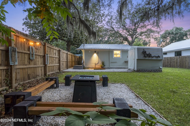 entry to storm shelter with a fenced backyard, a lawn, and an outdoor structure