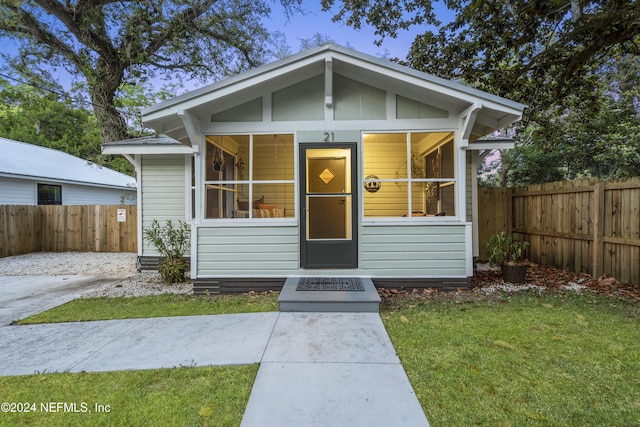 bungalow-style house featuring a front lawn and fence
