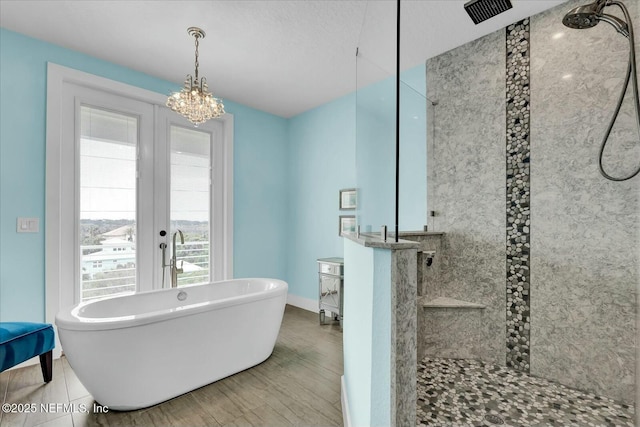 full bath with french doors, a chandelier, a freestanding tub, and a walk in shower