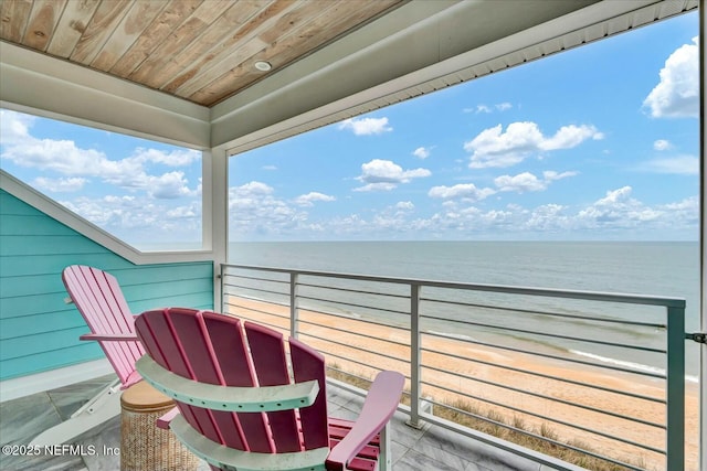 balcony with a water view and a view of the beach