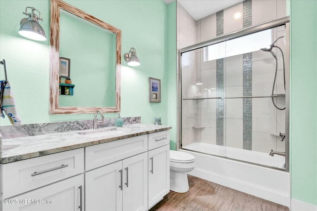 full bathroom featuring toilet, vanity, enclosed tub / shower combo, and wood finished floors