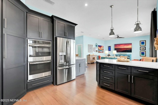 kitchen featuring light countertops, decorative light fixtures, visible vents, light wood-style flooring, and appliances with stainless steel finishes