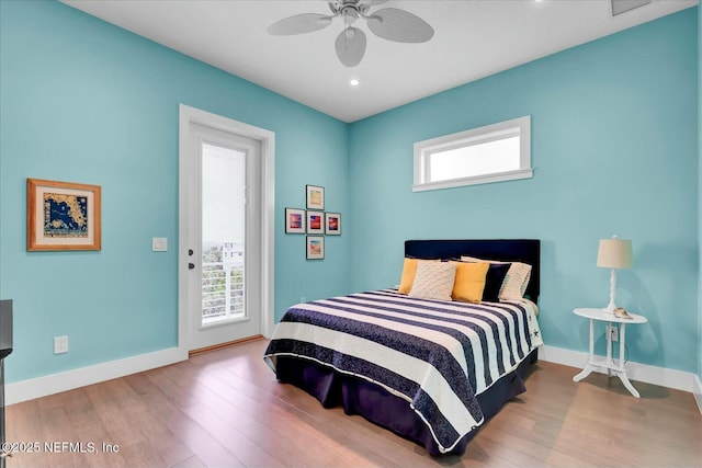 bedroom with access to outside, wood finished floors, and multiple windows