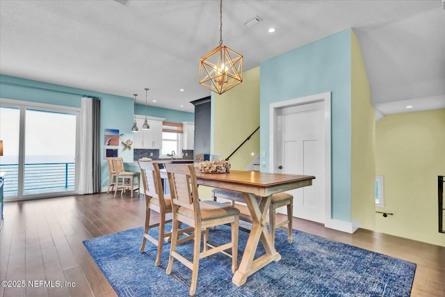 dining space featuring stairs, dark wood-type flooring, visible vents, recessed lighting, and an inviting chandelier