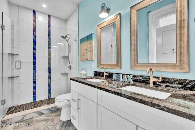 bathroom featuring a shower stall, double vanity, toilet, and a sink