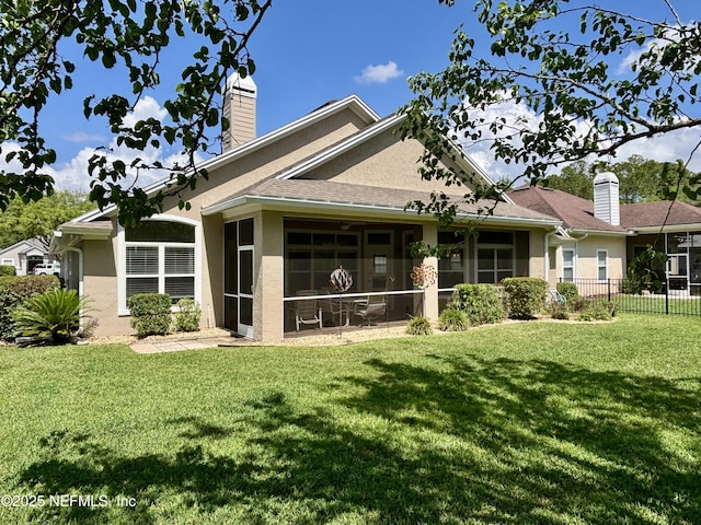 rear view of property with a sunroom, a yard, and stucco siding