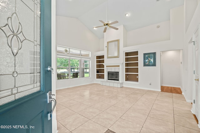 unfurnished living room with light tile patterned floors, built in shelves, baseboards, high vaulted ceiling, and ceiling fan