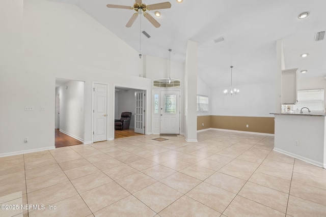 unfurnished living room with ceiling fan with notable chandelier, visible vents, high vaulted ceiling, and light tile patterned flooring