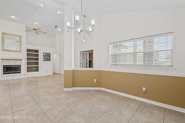 unfurnished living room with tile patterned flooring, built in features, baseboards, and ceiling fan with notable chandelier