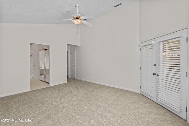 unfurnished bedroom featuring a textured ceiling, baseboards, visible vents, carpet, and high vaulted ceiling