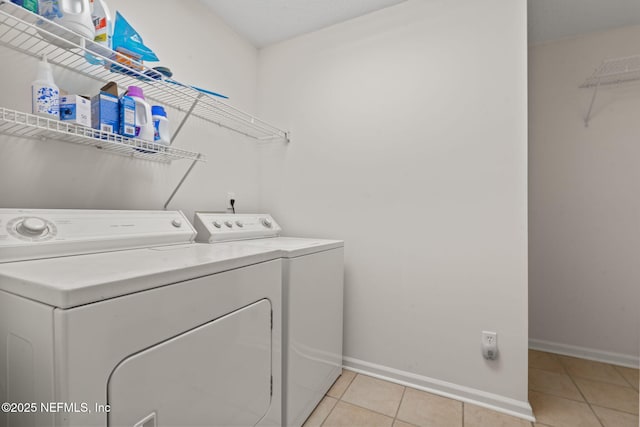 washroom featuring light tile patterned flooring, baseboards, washer and dryer, and laundry area