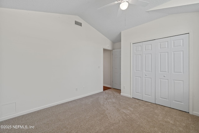 unfurnished bedroom featuring a closet, baseboards, lofted ceiling, carpet flooring, and visible vents