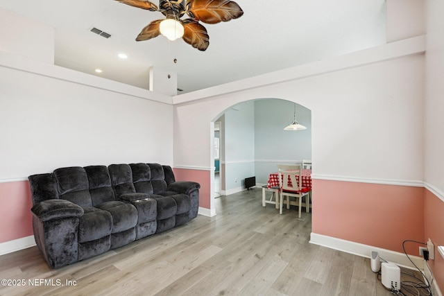 living room featuring a ceiling fan, arched walkways, wood finished floors, baseboards, and recessed lighting