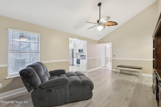 living room featuring a ceiling fan, light wood-style floors, healthy amount of natural light, baseboards, and lofted ceiling