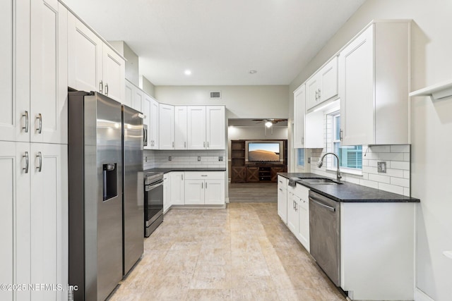 kitchen with appliances with stainless steel finishes, a sink, white cabinets, backsplash, and ceiling fan