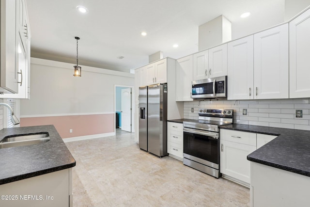 kitchen with stainless steel appliances, a sink, dark countertops, decorative backsplash, and white cabinetry