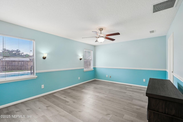 spare room featuring a ceiling fan, a textured ceiling, wood finished floors, and baseboards