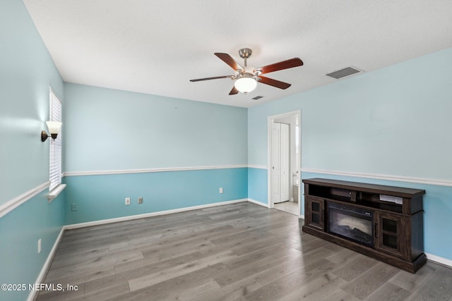 unfurnished room featuring a ceiling fan, wood finished floors, and baseboards