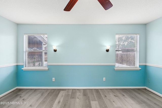 unfurnished room featuring ceiling fan, wood finished floors, and baseboards